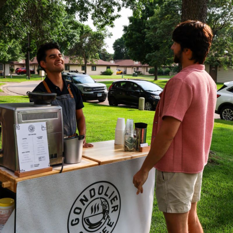 Friendly barista serving craft coffee at an outdoor Minneapolis event from the mobile coffee cart